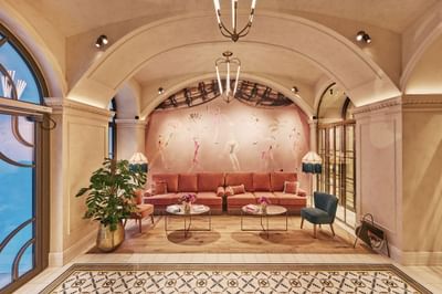 Elegant lounge with pink seating, decorative plants, and a colorful wall mural at Hotel Motto Vienna