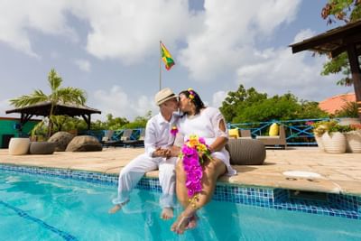A wedded couple dipping legs in the pool at True Blue Bay Hotel