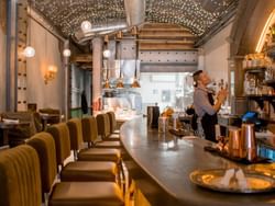 Rabbit Hole restaurant interior features a curved bar with green stools, and a visible kitchen area, near ReStays Ottawa