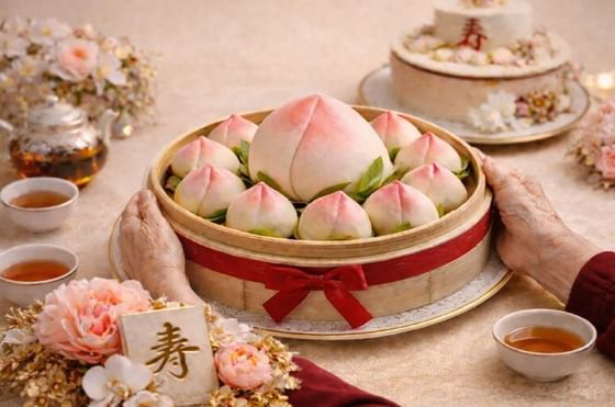 Traditional Chinese longevity peach buns presented in a bamboo steamer basket at Carlton Hotel Singapore