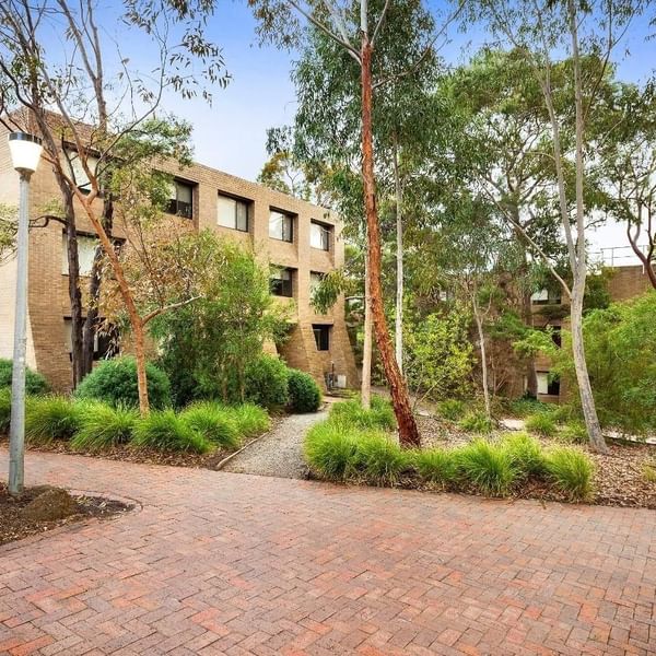 Brick pathway with trees and buildings at La Trobe University - Chisholm College.