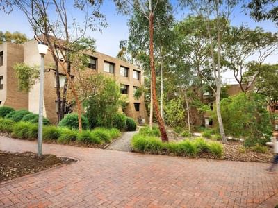 Brick pathway with trees and buildings at La Trobe University - Chisholm College.