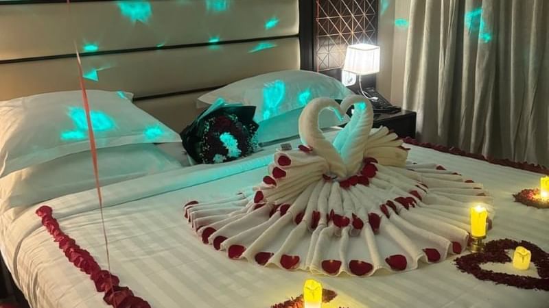 Room at Warwick Hotels and Resorts, decorated for a romantic evening with rose petals, candles, and a towel swan on the bed