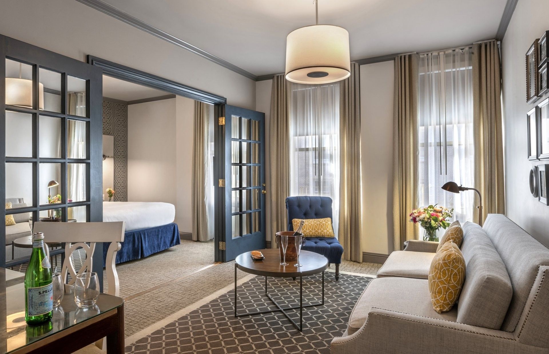 Living area by glass doors under a drum lamp near a sofa and armchair in Grand Suite at Warwick San Francisco