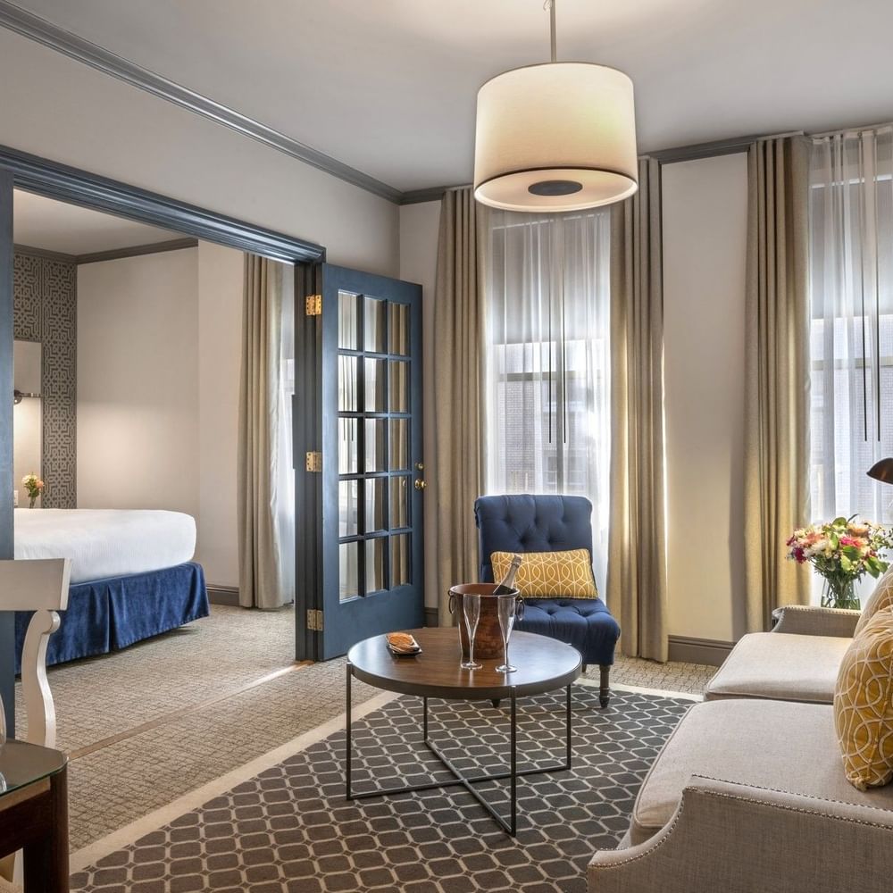 Living area by glass doors under a drum lamp near a sofa and armchair in Grand Suite at Warwick San Francisco