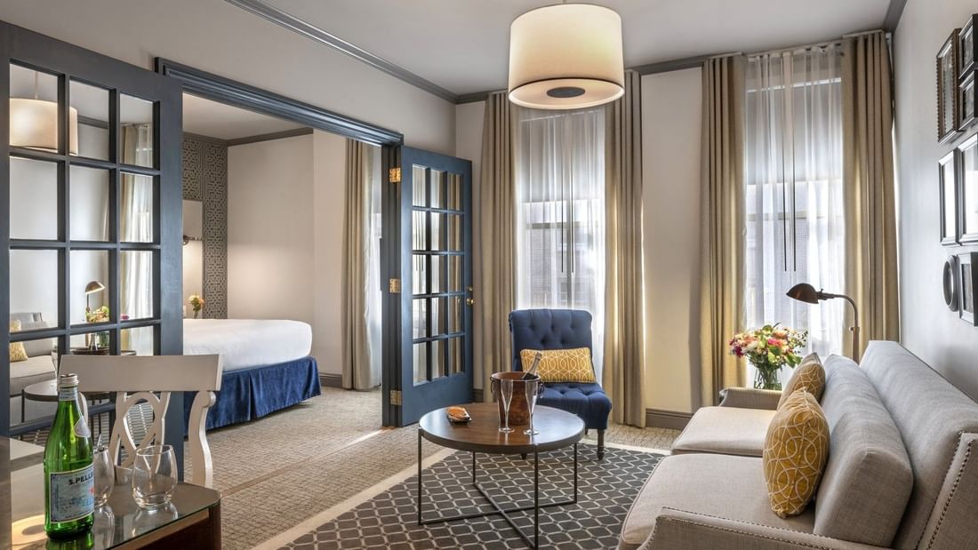Living area by glass doors under a drum lamp near a sofa and armchair in Grand Suite at Warwick San Francisco