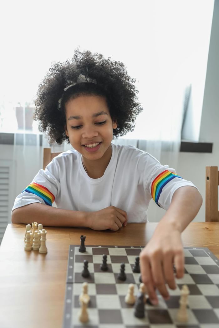 Child playing chess by a window at Anaheim Portofino Inn, an affordable hotel across from Disneyland with family suites