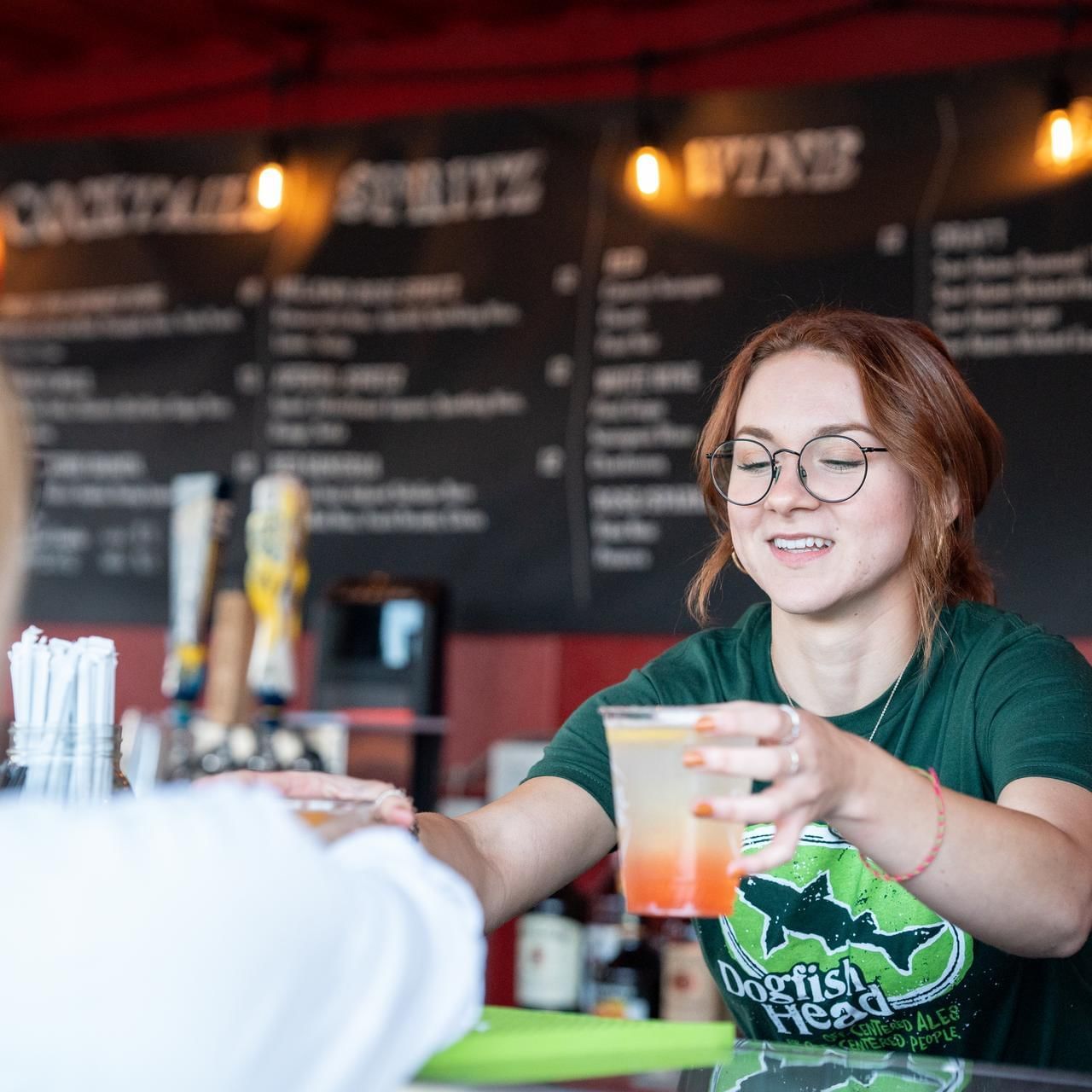 Barista handing over drinks to a guest by the counter in Beer Garden at The Artisan Hotel at Tuscan Village