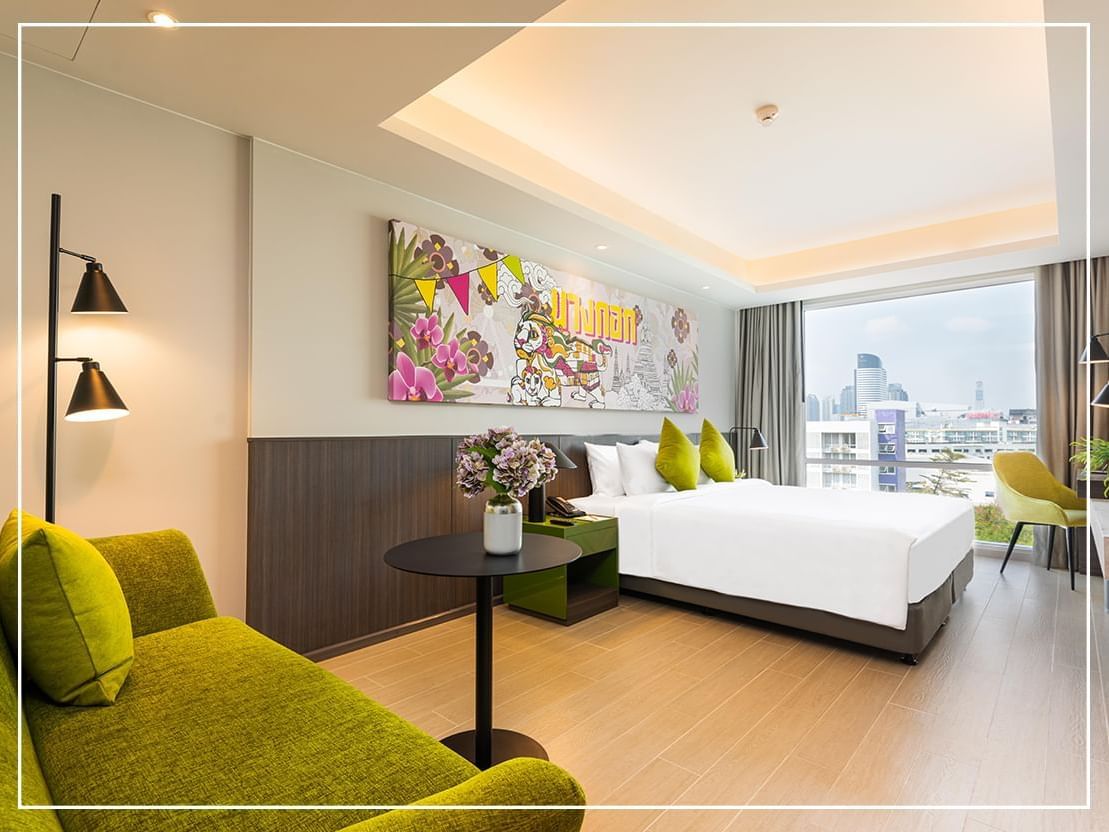 Bed & a couch in a Deluxe King Room at Maitria Hotel Rama 9