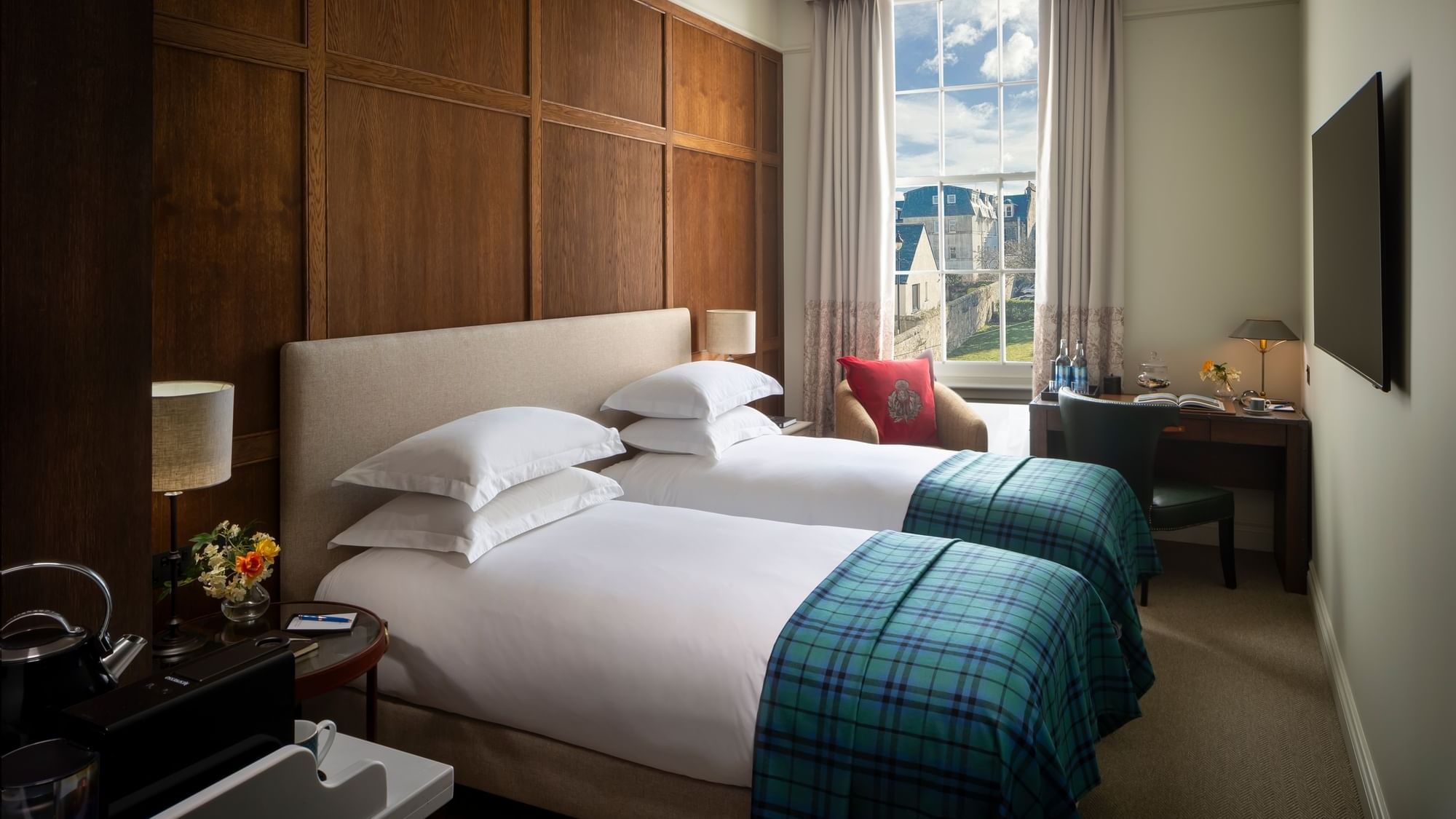 Two beds with an armchair and a work desk by the window in Deluxe Twin at Seaton House