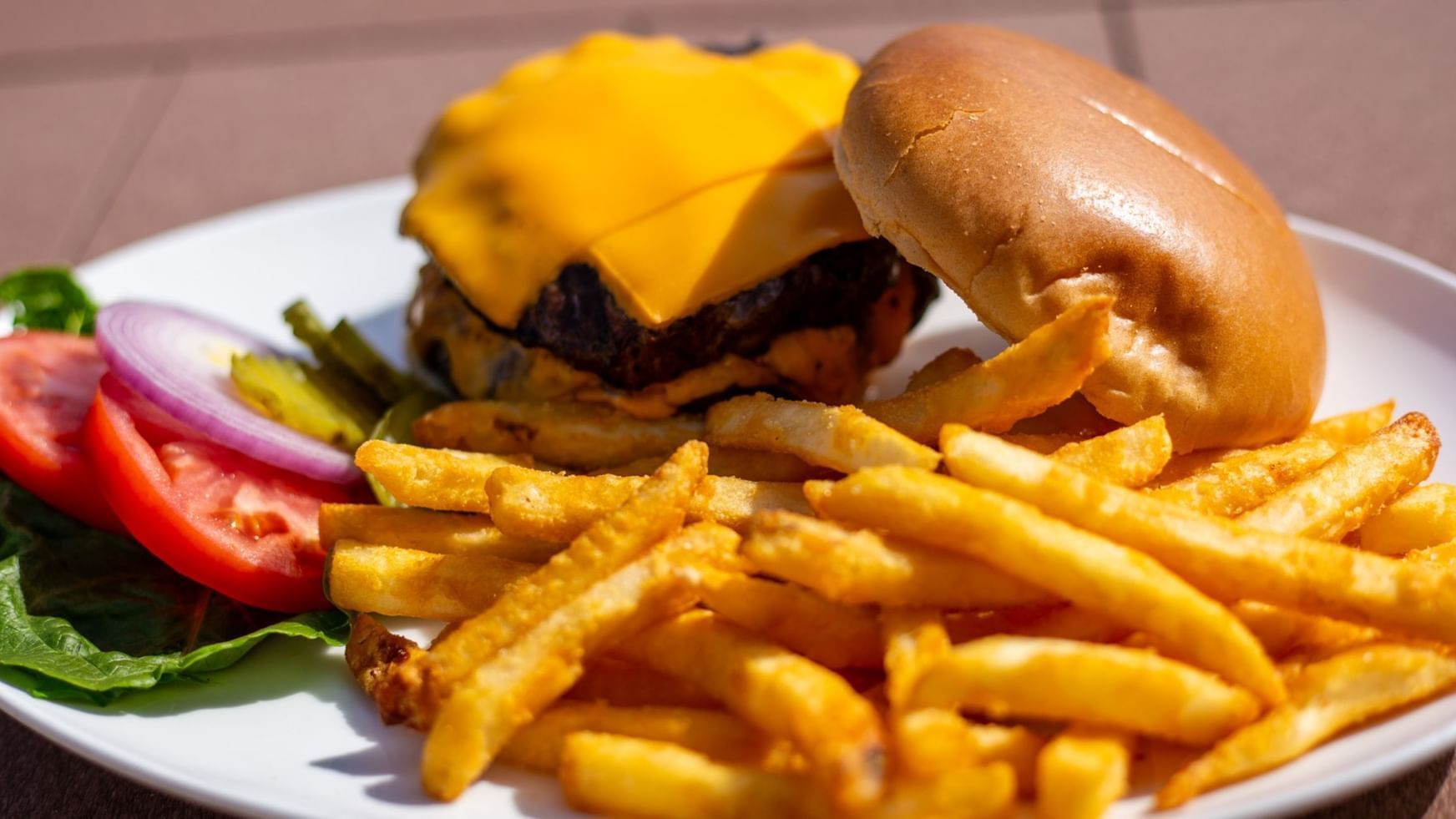 Plate featuring a cheeseburger with fries served in Doc's Bar and Grill at Shangri-La Monkey Island