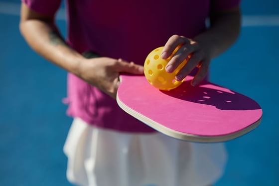 A person holding a Pickleball racket & a ball at Maui Coast Hotel