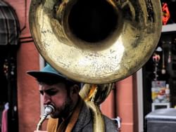 A man playing a tuba in the streets near the hotel