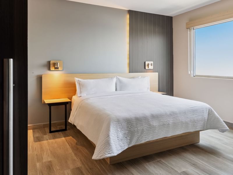 Cozy bed with a window view in Junior Suite King at Gamma Hotels