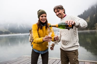 A couple standing on a deck, having champagne near Liebes Flueh