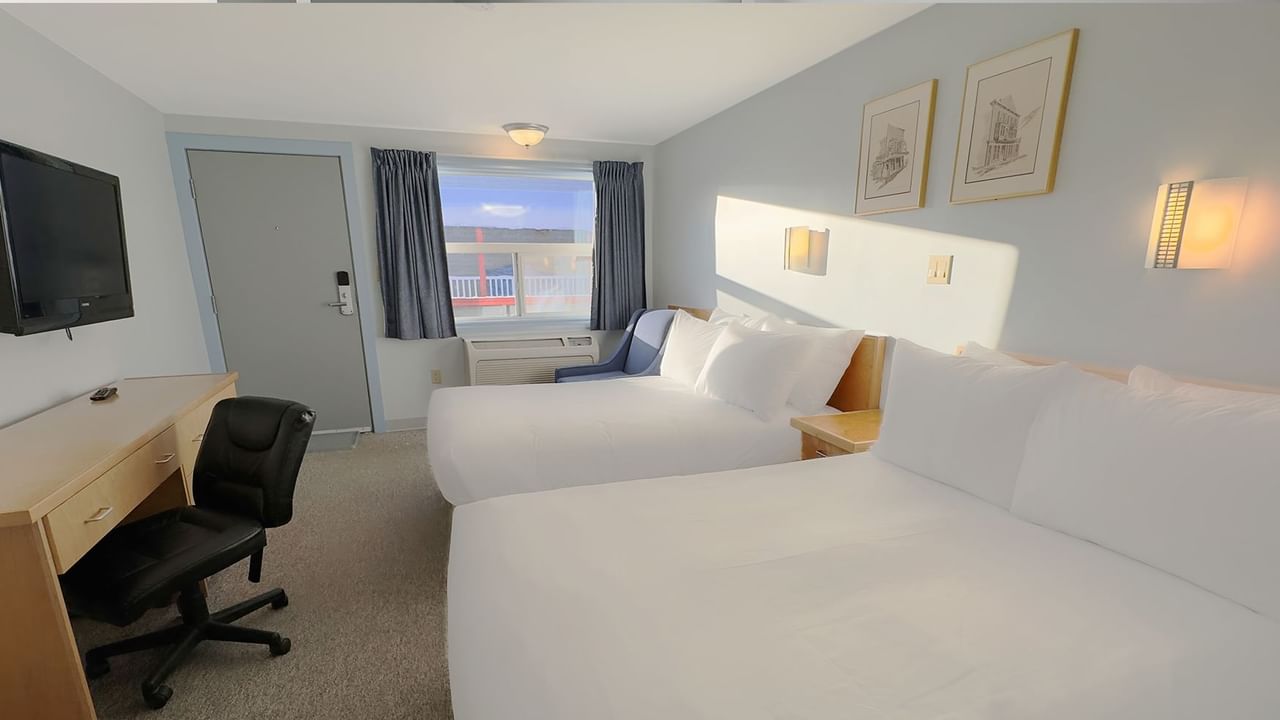 Two double beds, a work desk and a chair in front of a window