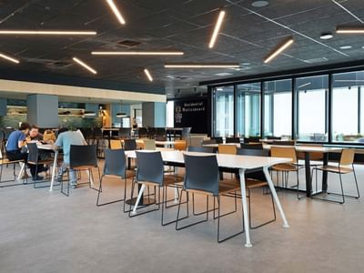 People dining at tables in a modern student accommodation cafeteria.