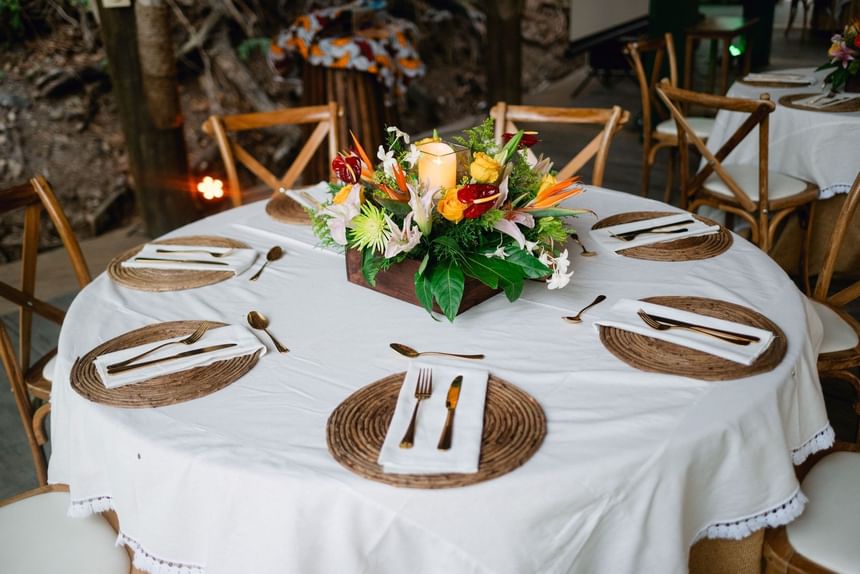 Floral centerpiece by a lit candle on a white table at Morgan's Rock Reserve & Ecolodge