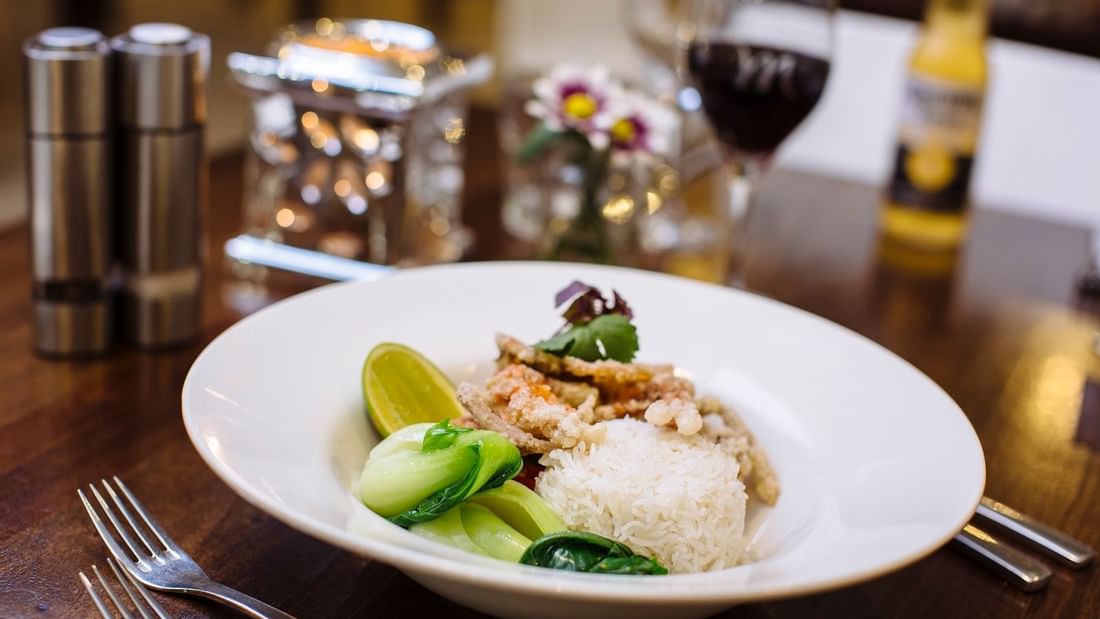 Plate of rice with crispy fish, and lime garnish, on a table in Celsius Restaurant & Bar at Mercure Hotel Townsville