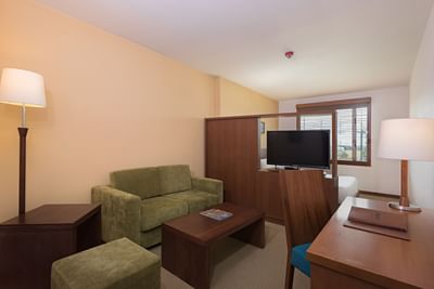 Spacious living area at Habitel Hotel Select with a green sofa, a coffee table, and a work desk near the window in Superior