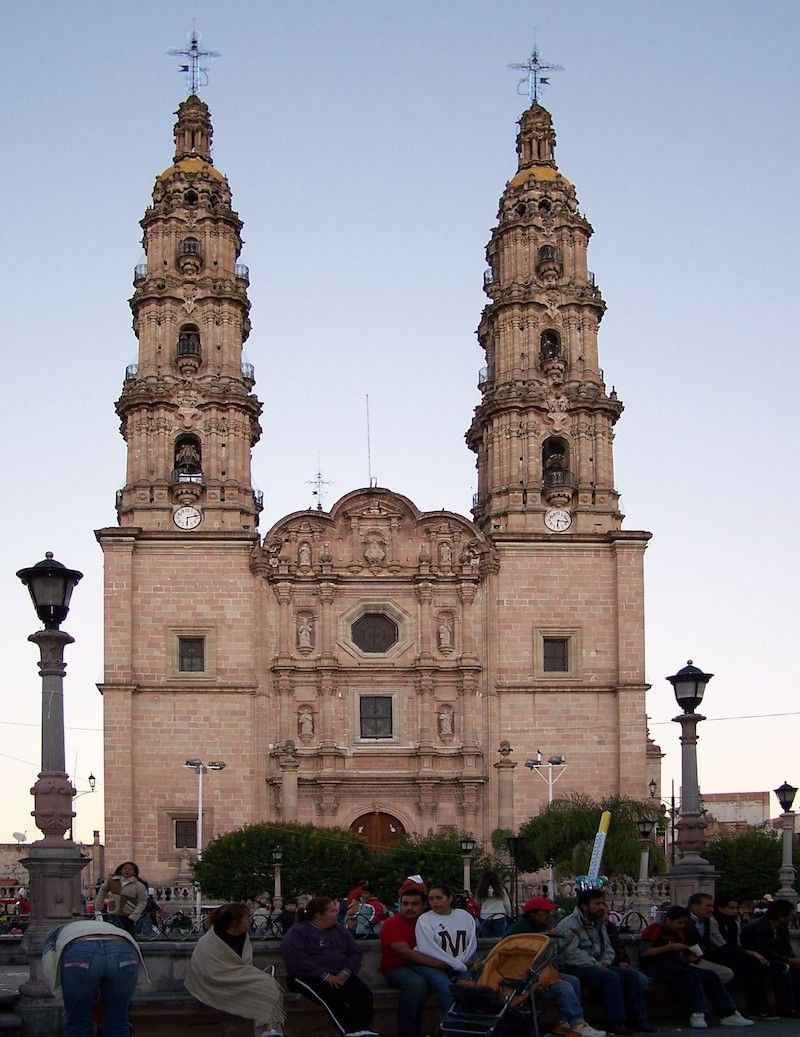 Facade of the Cathedral Basilica of San Juan de los Lagos, a large, pink stone building with twin spires near Real Inn Nuevo Laredo