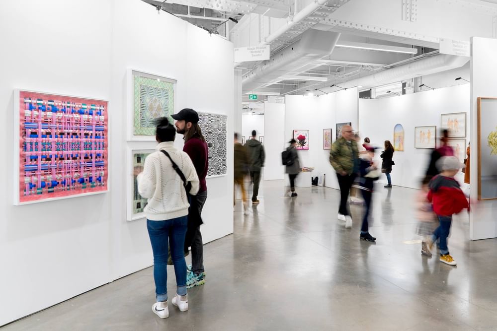 Visitors viewing colorful contemporary artwork in a bright modern art gallery with white walls and exposed ceiling at Warwick Le Crystal Montreal