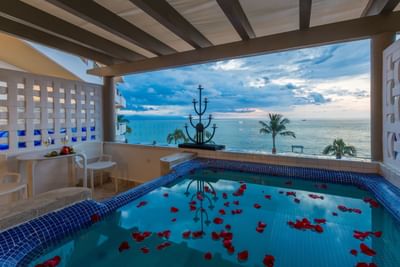 A luxury private balcony featuring an outdoor jacuzzi overlooking the blue ocean waters.