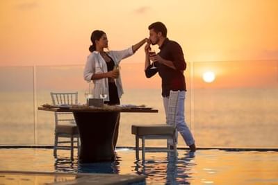 Man kissing woman's hand at sunset table by infinity pool at Playa Los Arcos Puerto Vallarta 2023