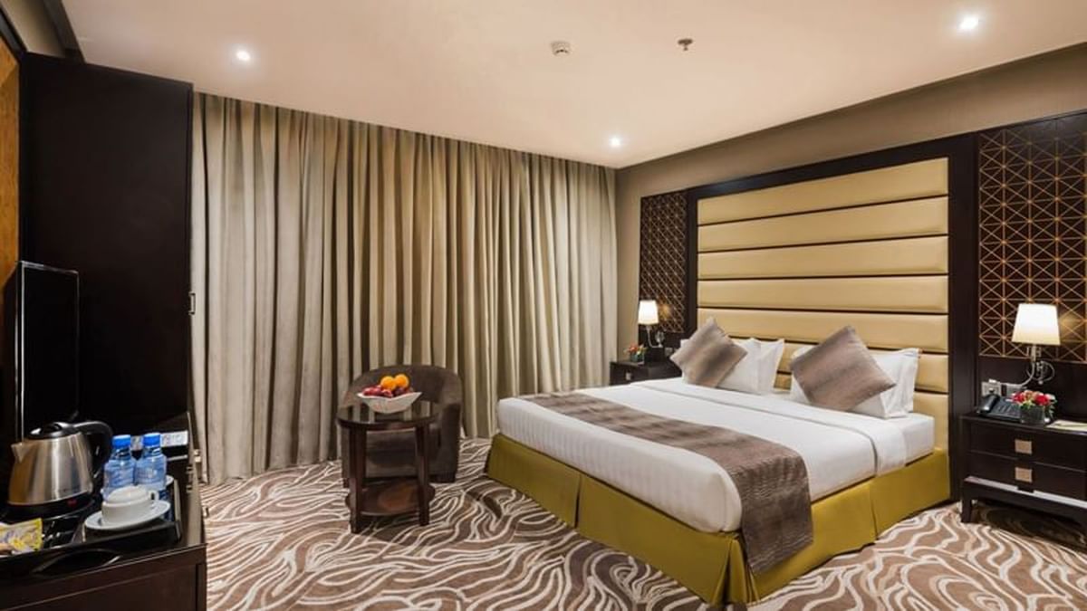Fruit bowl on a table by an chair under heavy drapes near the bed in Deluxe King / Twin Room at Naviti by Warwick Al Khobar