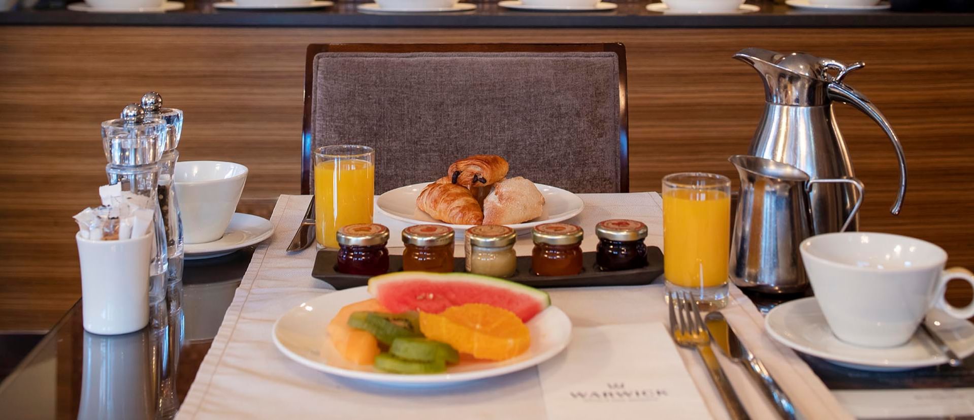 Well-set breakfast table featuring fresh fruit, croissants, & orange juice at Téséo Restaurant