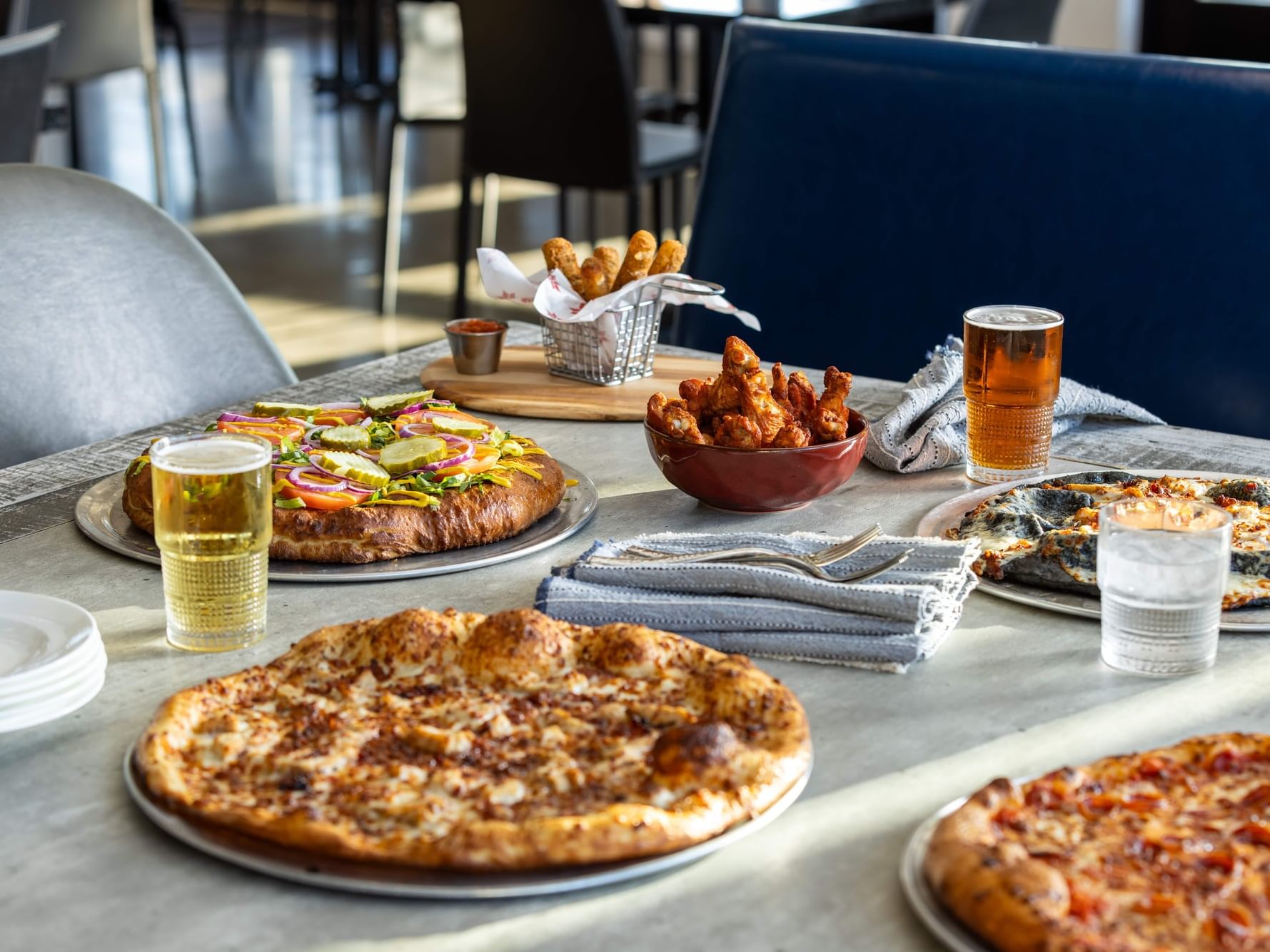 Plates of pizzas and fries with drinks at Anchor Crust Co. at Shangri-La Resort