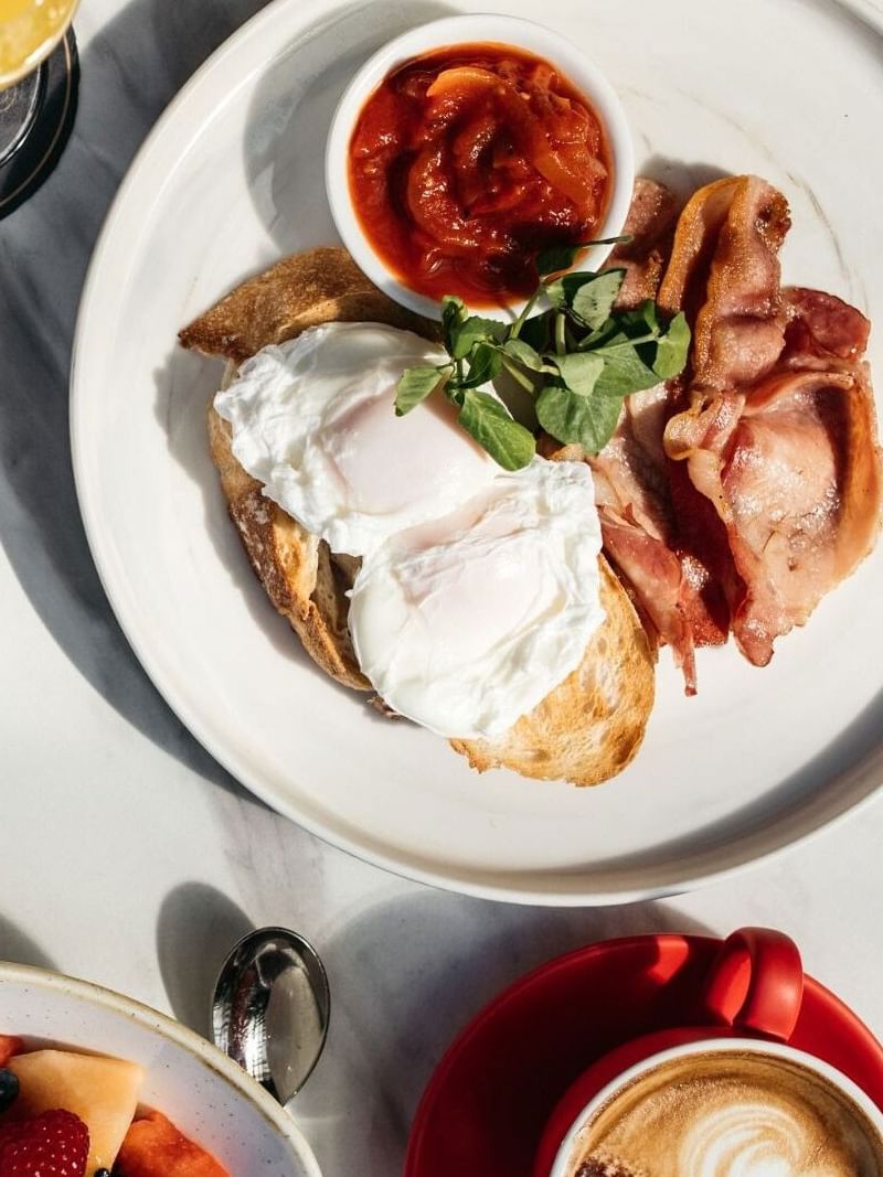 Breakfast at Elysium Manly with poached eggs on toast, crispy bacon under bright light, one of the best Ciboria Manly