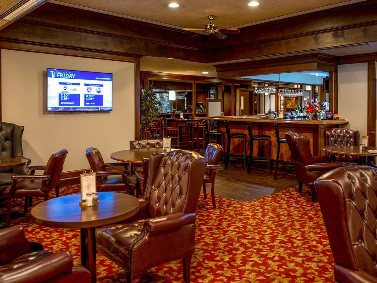 Interior of Winston's Resto-Bar with leather chairs, red carpet, and two TVs.