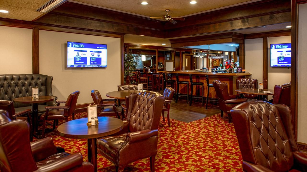 Interior of Winston's Resto-Bar with leather chairs, red carpet, and two TVs.