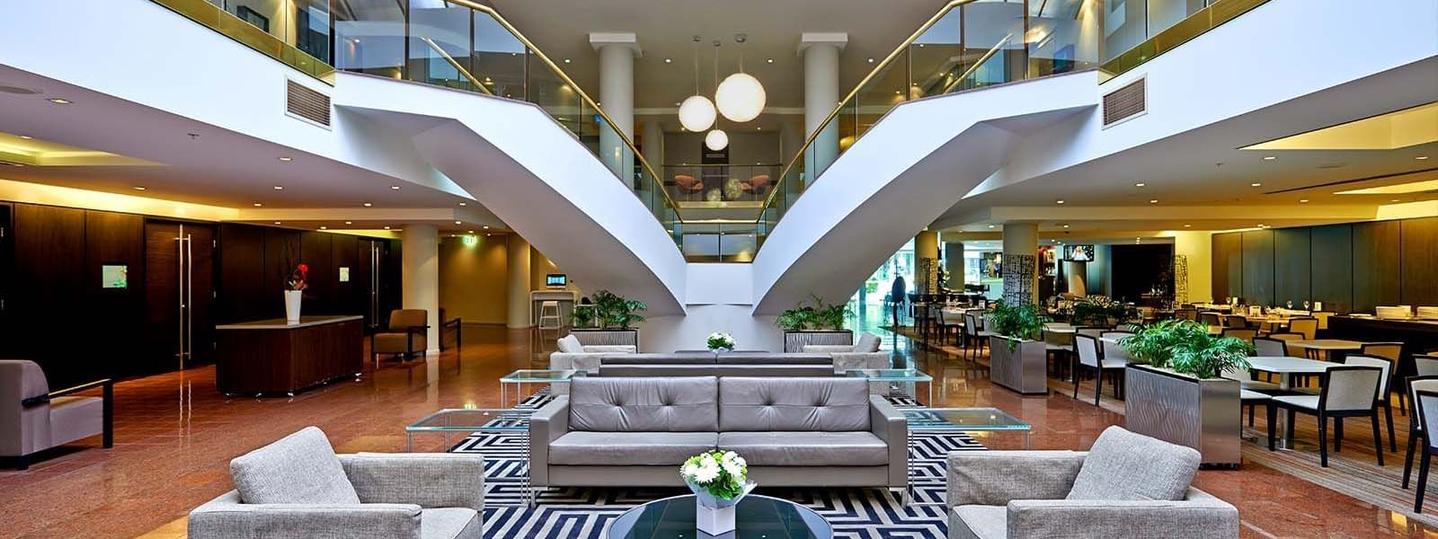 Modern atrium lounge with elegant furniture and glass staircases at Novotel Sydney Parramatta.