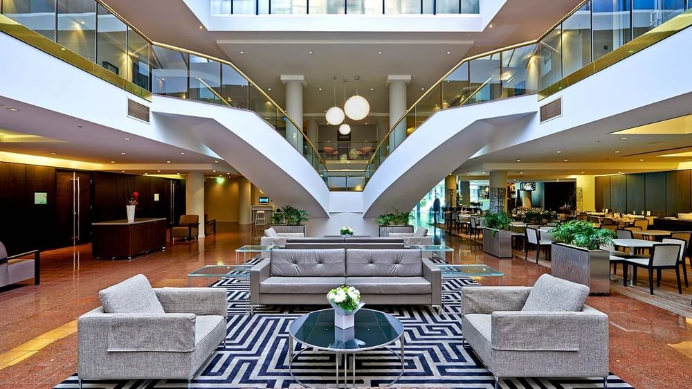 Modern atrium lounge with elegant furniture and glass staircases at Novotel Sydney Parramatta.