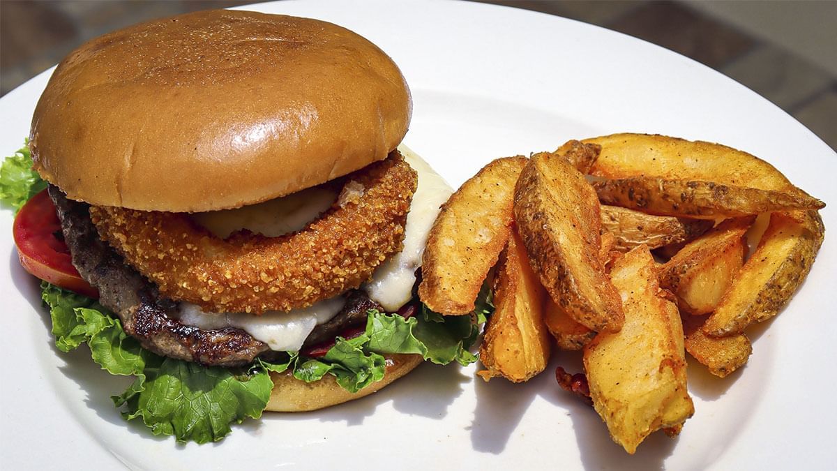 Hamburguesa empanizada con queso, lechuga y tomate, con papas sazonadas en La Pérgola de Araiza Palmira 