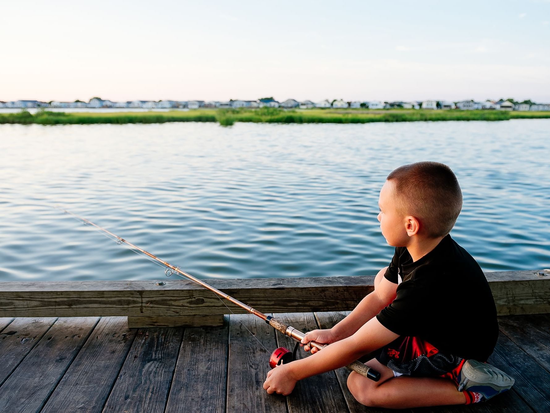 A kid fishing on a dock by the lake near Holiday Inn Hotel