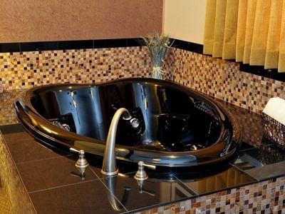 Close-up of a jetted tub with a wall of warm, colorful mosaic tiles in Deluxe Two Bedroom Suite at Americana Village Suites