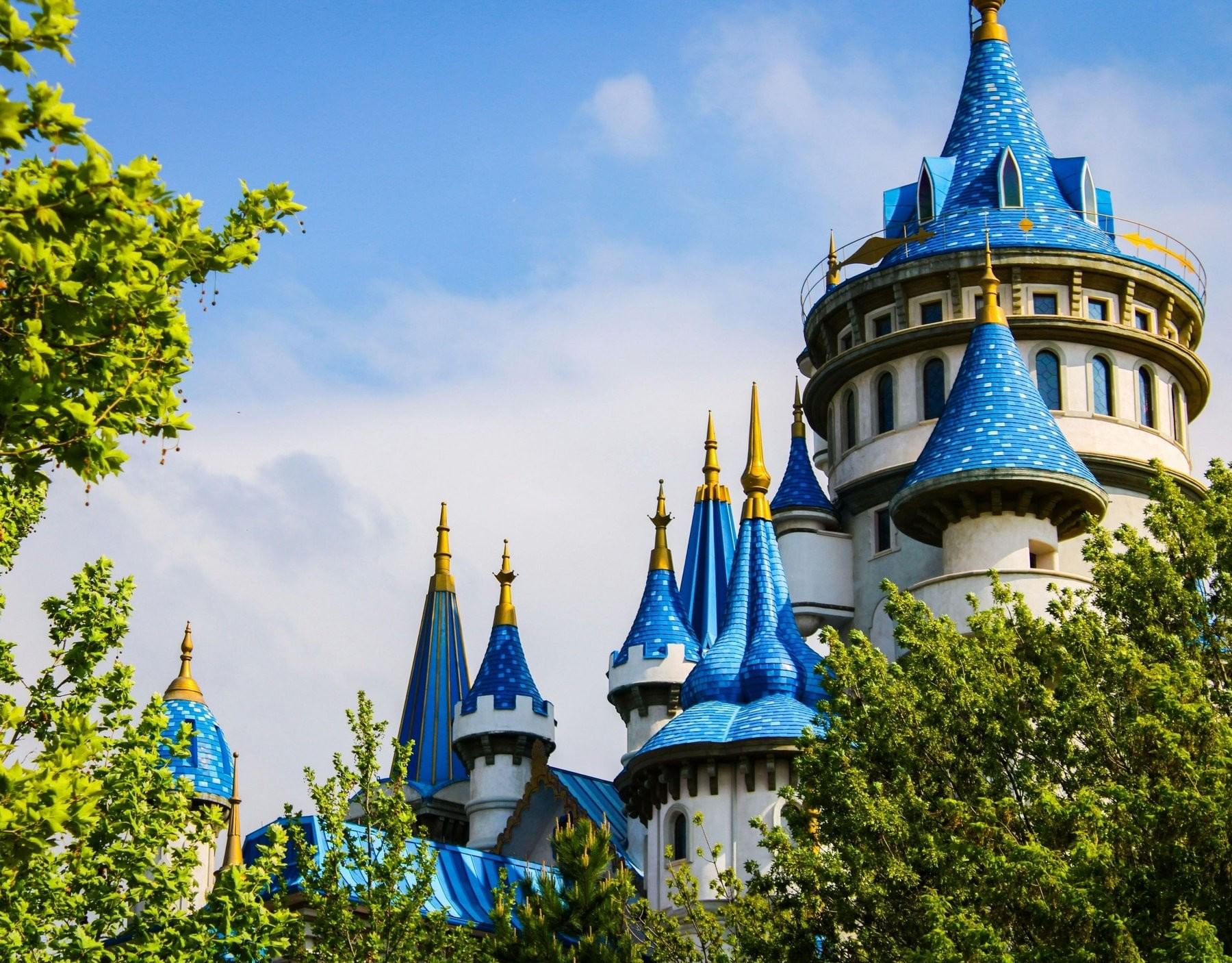 Close-up of blue & gold castle turrets surrounded by trees near The Inn at Celebration, things to do in Celebration FL