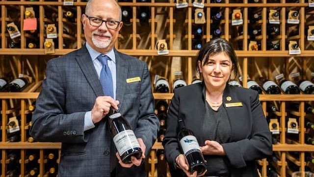 Sommeliers of Chateaux Deer Valley, Jim Dahlgren and Eliza Perkins presenting wine bottles