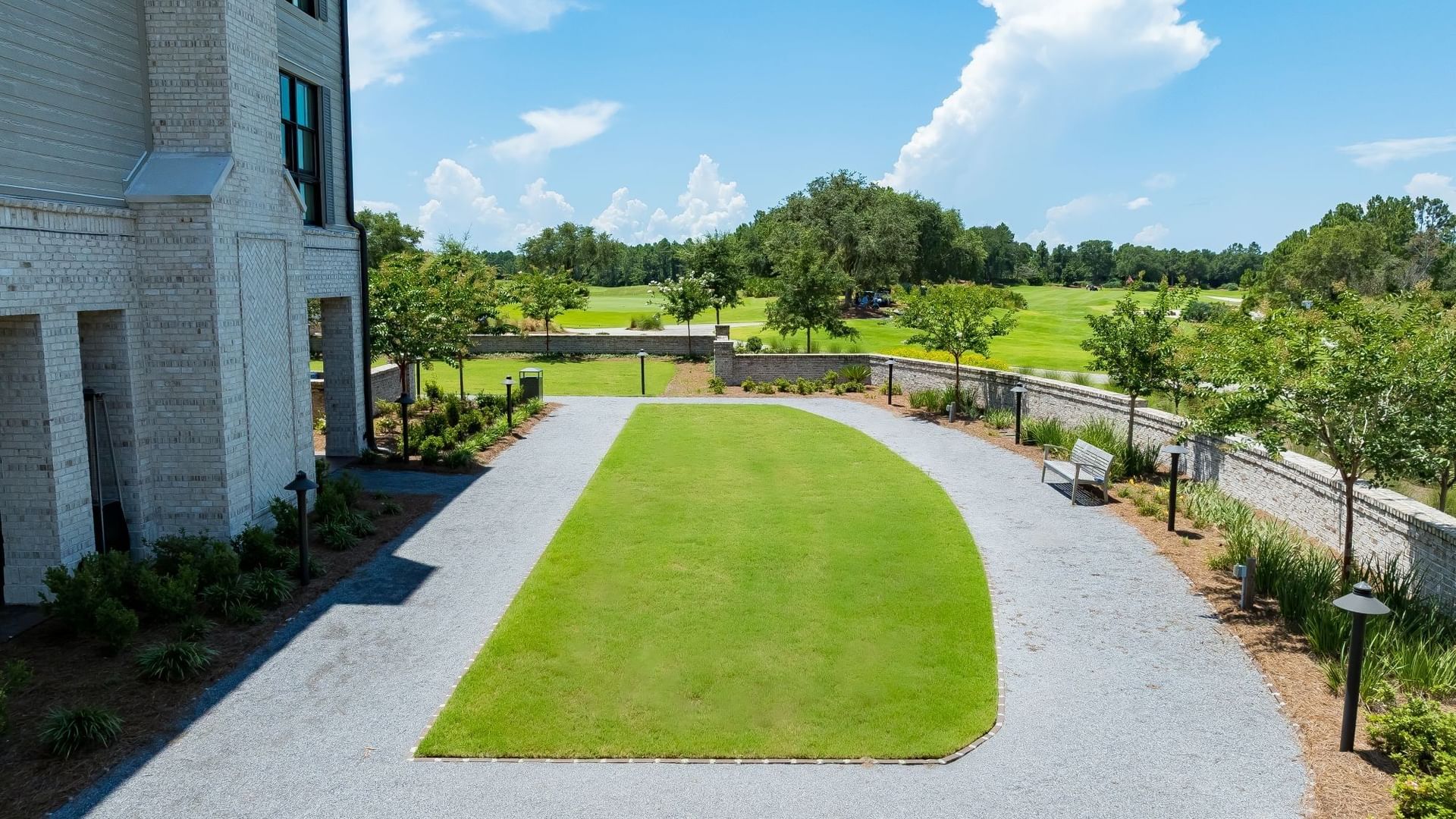 Manicured green lawn surrounded by gravel patio with landscaping and golf course views at Camp Creek Inn in Inlet Beach.