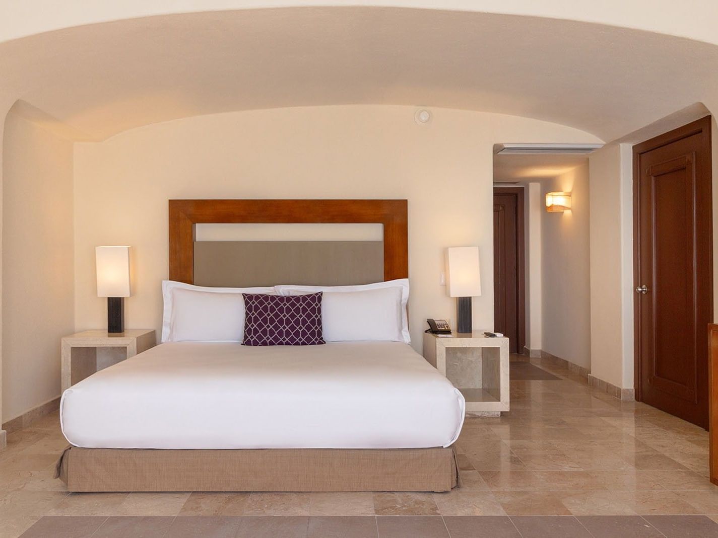 Nightstands by the bed with white linens in the Partial Ocean View Deluxe King Room at Camino Real Acapulco Diamante