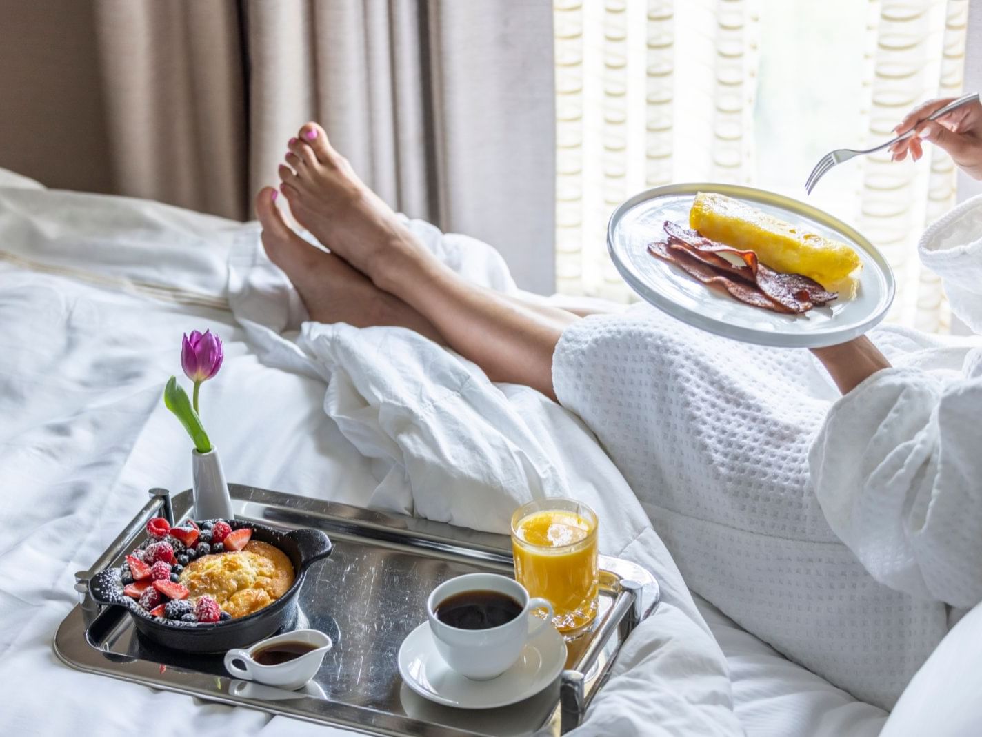 A lady enjoying breakfast on a bed in a room at Townsend Hotel