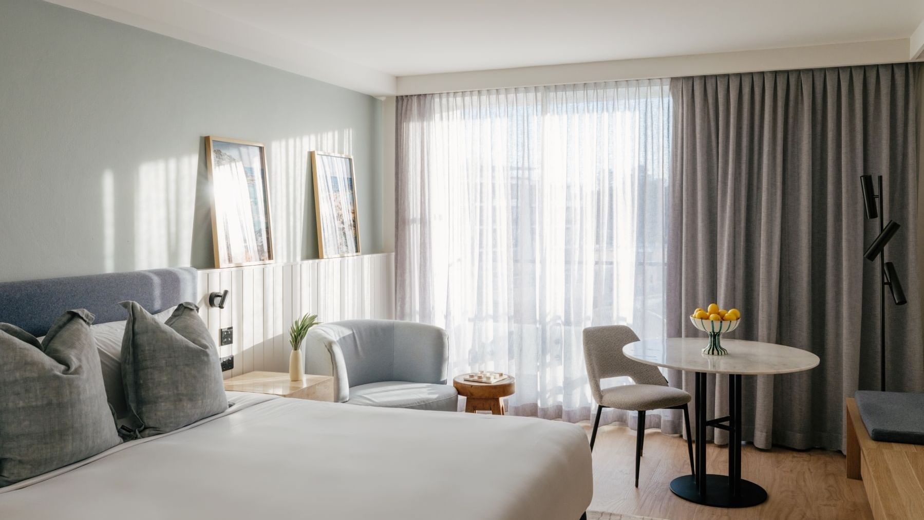 Sunset View King at Elysium Manly with a lemon bowl on a round marble table by sheer curtains under a light blue armchair