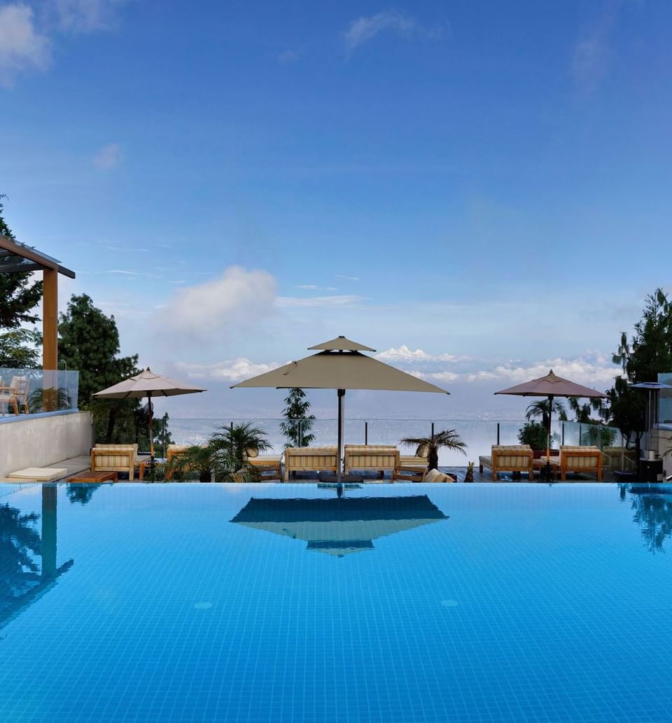 Infinity pool with umbrellas and lounge chairs overlooking the sky at The Terraces Resort & Spa