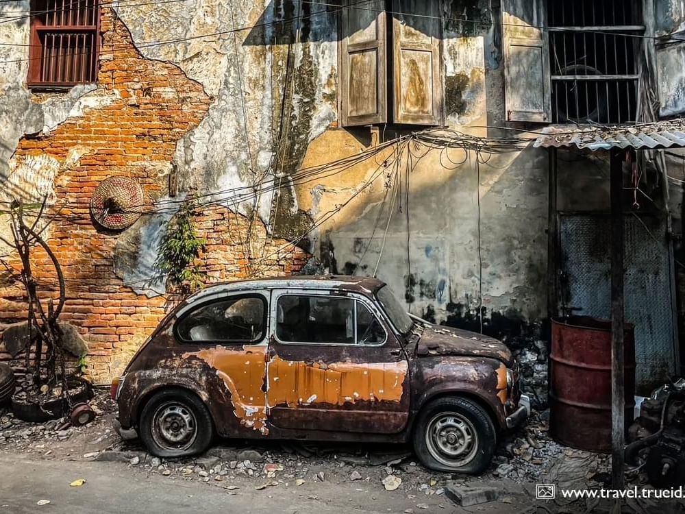  A vintage car stands still before an aged building, highlighting the charm of classic vehicles and historical architecture.