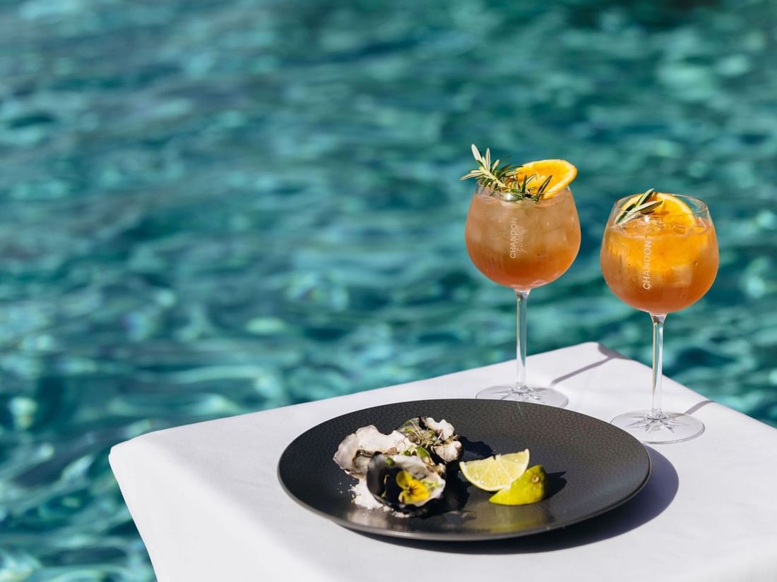 Plate of oysters and two drinks by the pool at Pullman Bunker Bay Resort