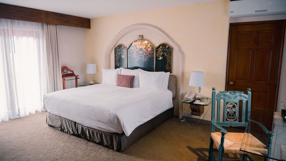 King Presidential Suite featuring a hand-painted headboard and colonial-style chair at Quinta Real Zacatecas