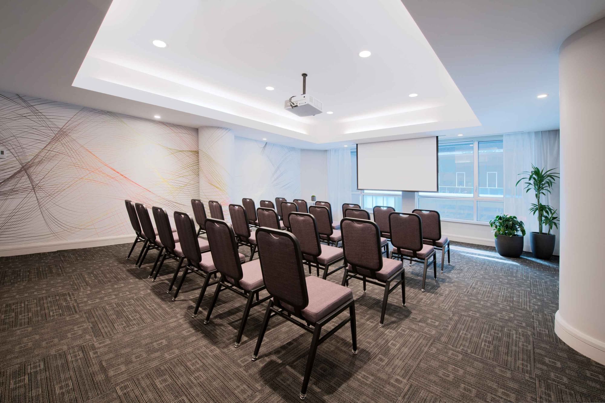 Theatre set-up with a projector screen and carpeted floors in Salon Drummond at Warwick Hotels and Resorts